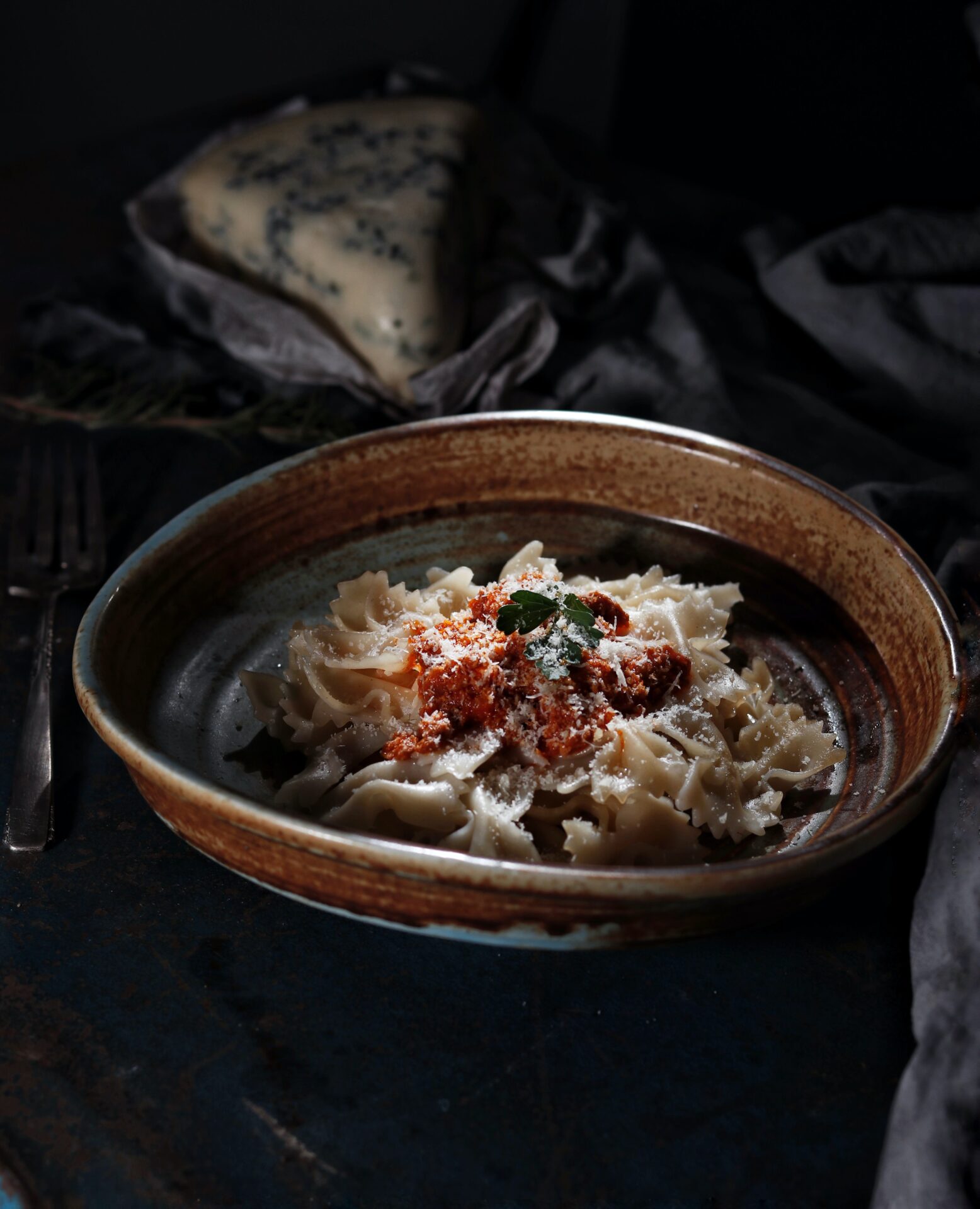 A bowl of pasta with sauce and herbs.