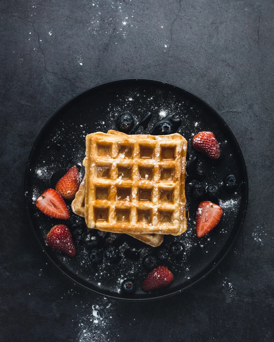 A waffle with strawberries on top of it.